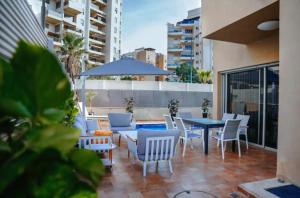 une terrasse avec une table, des chaises et un parasol dans l'établissement O&O Group - Prestigious Beachfront Villa W Private Pool, à Rishon LeẔiyyon