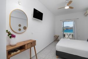 1 dormitorio con cama, espejo y TV en ILIAS SEA VIEW, en Pollonia