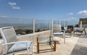 un grupo de sillas sentadas en la parte superior de un balcón en נוף העמק - דירה מהממת בצפת עם נוף עוצר נשימה - 3Bdrm Apartment with Sea of the Galilee View in Tzfat, en Nof Kinneret
