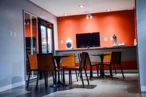 une salle à manger avec une table, des chaises et une télévision dans l'établissement Hotel São Domingos, à Feira de Santana