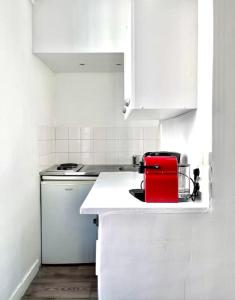 une cuisine blanche avec un appareil rouge sur un comptoir dans l'établissement Appartement de charme tout équipé à Paris, pour 4 personnes, 2 grands lits, à Levallois-Perret