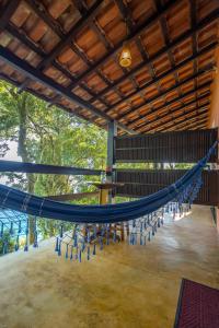 a hammock in a room with chairs and a table at Pousada Lagamar in Praia Vermelha