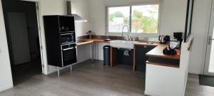 kuchnia z czarną lodówką i zlewem w obiekcie Saint Côme Beach House w mieście Saint-Côme-de-Fresné