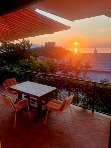 a table and chairs on a balcony with a sunset at Apartments Varga in Senj