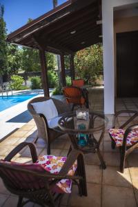 a patio with chairs and a table and a pool at El Marco Villa in Pissouri