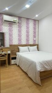 a bedroom with a white bed and a desk and a bed sidx sidx at KIM HOUSE in Danang