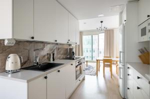 a white kitchen with a sink and a table at Studio Lumilinna in Tampere