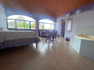 Schlafzimmer mit einem Bett, einem Tisch und Fenstern in der Unterkunft Casa Morada in Bernal