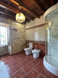 uma casa de banho com 2 WC e uma cabina de duche em vidro. em Casa de Romaxe em Muros