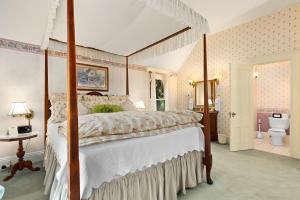 a bedroom with a canopy bed and a bathroom at The Gables Wine Country Inn in Santa Rosa