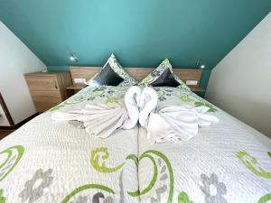 a bed with a white comforter with two bows at Pension Seepferdchen in Norddeich