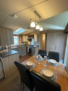 a dining room table with chairs and a kitchen at Millfields Holiday Park - Diamond Deluxe - Coastal Caravan Breaks in Ingoldmells +7 photos