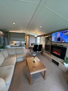 a living room with a couch and a flat screen tv at Millfields Holiday Park - Diamond Deluxe - Coastal Caravan Breaks in Ingoldmells