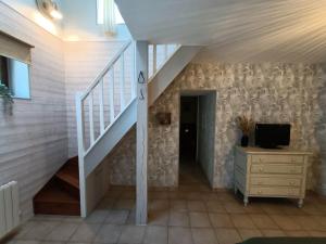 a hallway with a staircase with a tv and a dresser at Le Moulin de Benneville chambres d'hôtes, petit déjeuner compris in Cahagnes