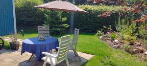stół, dwa krzesła i parasol na dziedzińcu w obiekcie The Holcombe Hut, Ridgefield House w mieście Longdown