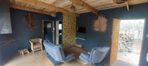a living room with two blue chairs and a window at Hartbeest Eco Bush Lodge 3 in Hartbeespoort