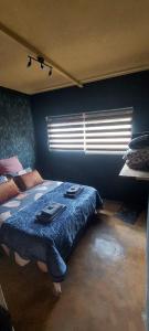 a bedroom with a bed with blue walls and a window at Hartbeest Eco Bush Lodge 3 in Hartbeespoort