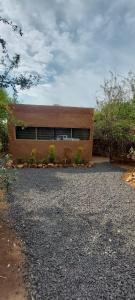 a house sitting on top of a gravel driveway at Hartbeest Eco Bush Lodge 3 in Hartbeespoort