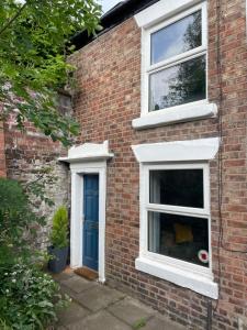 a brick house with two windows and a blue door at Tucked away house in Macclesfield in Macclesfield