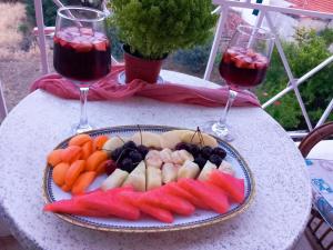 un plato de frutas y hortalizas en una mesa con dos copas de vino en Panorama en Methana