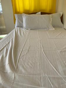 białe łóżko z białą pościelą i poduszkami w obiekcie Maria Kulafu Studio Apartment Kinamaligan- Beside Eglin Gas FREE Wifi w Masbate