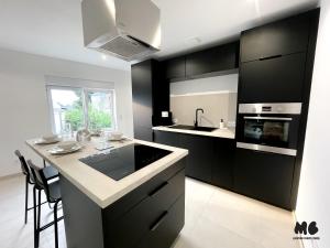 a kitchen with black and white cabinets and a counter at Maison Brigitte - Jacuzzi Videoprojecteur Xbox in Aulnoy