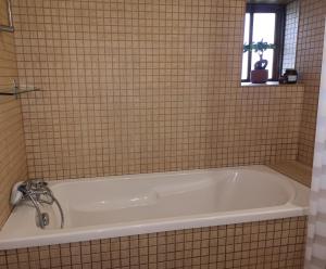 uma banheira numa casa de banho em azulejo com uma janela em Casa do Parâmio - Montesinho em Parâmio