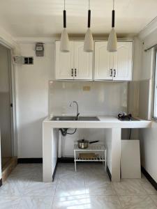 una cocina blanca con fregadero y armarios blancos en Maria Kulafu Studio Apartment Kinamaligan- Beside Eglin Gas FREE Wifi, en Masbate