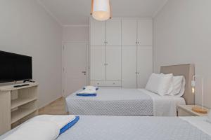 a white bedroom with two beds and a television at Mano's pool villa in Potamós