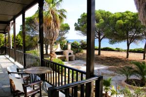 a porch with a table and chairs and a view of the ocean at The Sisters Beach House in Diliso
