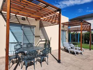 a patio with a table and chairs under a wooden pergola at Casa en Club de Campo. Parque y Pileta. in San Nicolás de los Arroyos