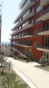 a red apartment building with a sidewalk in front of it at Shtepipushimi23 Rana e Hedhun in Shëngjin