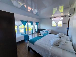 um quarto com 2 camas e 2 janelas em Hotel Cally em Puerto Villamil