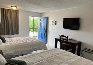 a bedroom with two beds and a tv and a desk at Ballparks Inn in Branson