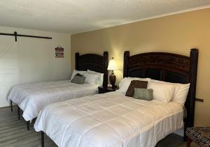 a bedroom with two beds with white sheets at Ballparks Inn in Branson