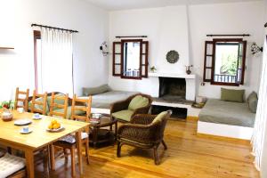 una sala de estar con mesa y sillas y una habitación con chimenea en The Sisters Beach House, en Vathírrevma