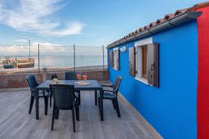 een tafel en stoelen op een balkon met een blauwe muur bij Burano L' Occhio sulla Laguna in Burano