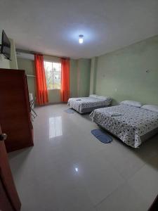 um quarto com duas camas e uma janela com cortinas vermelhas em Hotel las Acacias Hospedajes en Nueva Loja em Nueva Loja