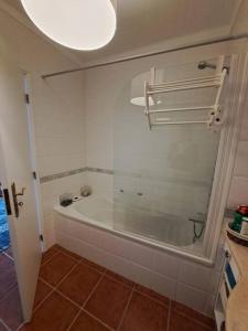 a bathroom with a bath tub with a glass window at Sunset House Porto de Barcas - 3 rooms & Terrace in Lourinhã