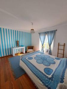 a bedroom with a bed with a blue and white blanket at Sunset House Porto de Barcas - 3 rooms & Terrace in Lourinhã