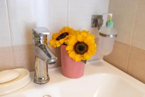 een roze vaas met gele bloemen op een wastafel bij CloisterVista apartment in Napels