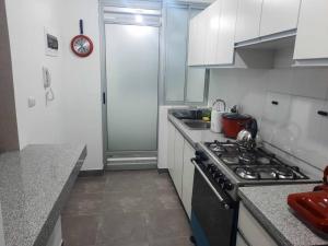 a kitchen with white cabinets and a stove top oven at Hermoso dpto en condominio residencial en estreno in Paucarpata