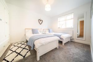 2 camas en un dormitorio con paredes blancas en Huckleberry - Premium, Hot Tub, x2 Parking, Farm Shop Next door, Private Cornish Lane en Newquay