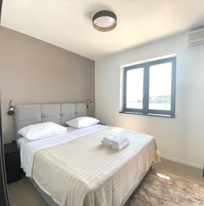 um quarto com uma grande cama branca e uma janela em Villa Jadrana em Rab