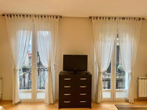 Sala de estar con 2 ventanas y TV en Suite Loft Laurel, en Logroño
