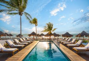 a pool at the beach with lounge chairs and palm trees at Fairmont Mayakoba Riviera Maya - All Inclusive in Playa del Carmen