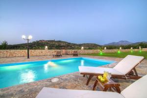 RoumelíにあるNestor Villa, with Private Pool & Absolute Privacyのラウンジチェアとテーブル付きのスイミングプールを提供しています。