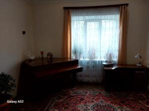uma sala de estar com um piano e uma janela em Дили Дом em Dilijan