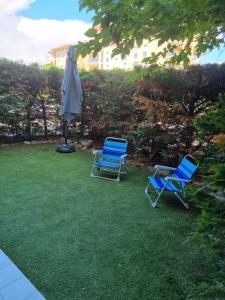 dos sillas azules y un paraguas en la hierba en Bel Appartement Frejus, en Fréjus