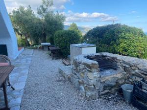 een stenen open haard in een tuin met een picknicktafel bij La Collina sul Mare in Campo nell'Elba